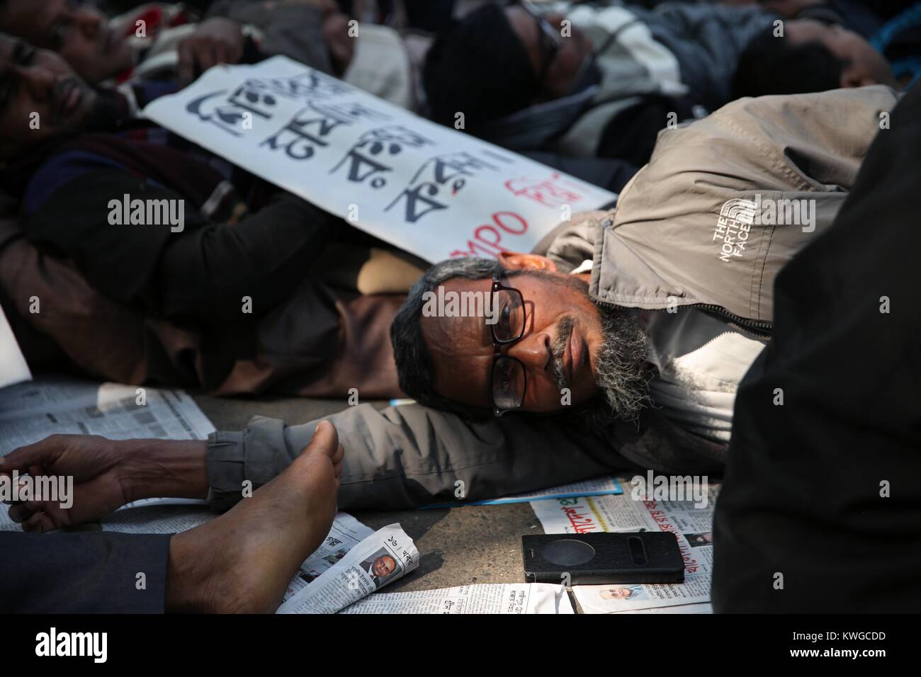 Dhaka, Bangladesh. 3rd Jan, 2018. Non-MPO (monthly pay order) teachers from different non-government institutions, lay down in the street as they continue the four day of their fast unto death hunger strike program in front of the National Press Club in Dhaka, Bangladesh, 03 January 2018. Some hundred teachers went for hunger strike demanding their inclusion of the government-approved educational MPO facilities while more than 80,000 teachers from 5,242 non-MPO institutions are working without any pay, according to the leaders. Credit: ZUMA Press, Inc./Alamy Live News Stock Photo