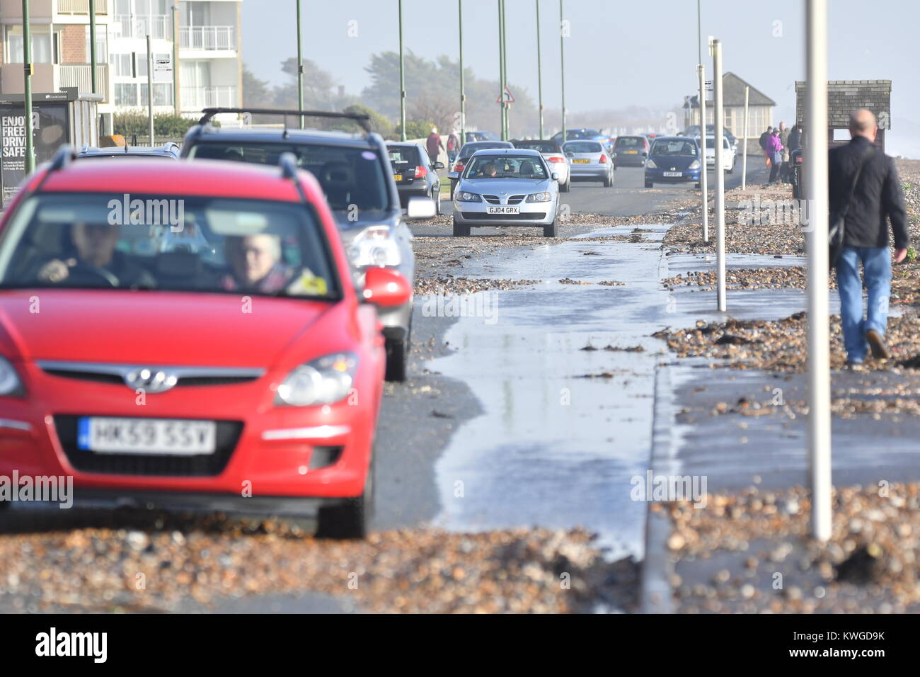 Sea Road, Rustington, West Sussex, England, UK. Wednesday 3rd January 2018. Cars battle through seawater and beach shingle on Sea Road in Rustington, after the windy conditions caused an abnormally high tide on the south coast. Credit: Geoff Smith/Alamy Live News Stock Photo
