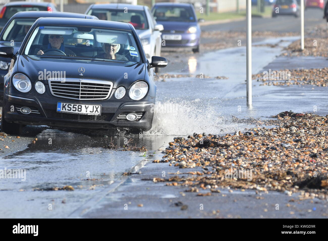 Sea Road, Rustington, West Sussex, England, UK. Wednesday 3rd January 2018. Cars battle through seawater and beach shingle on Sea Road in Rustington, after the windy conditions caused an abnormally high tide on the south coast. Credit: Geoff Smith/Alamy Live News Stock Photo