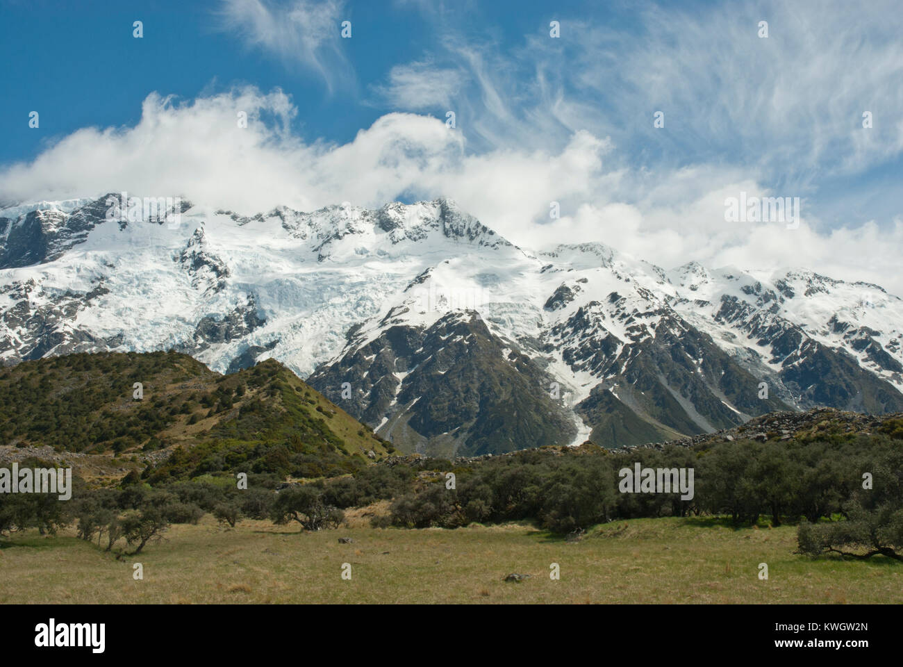 Stunning Hooker Valley in Southern Alps, snow capped Mount Sefton and range, an avalanche of snow, whispy clouds against blue sky. Spring/summer. Stock Photo