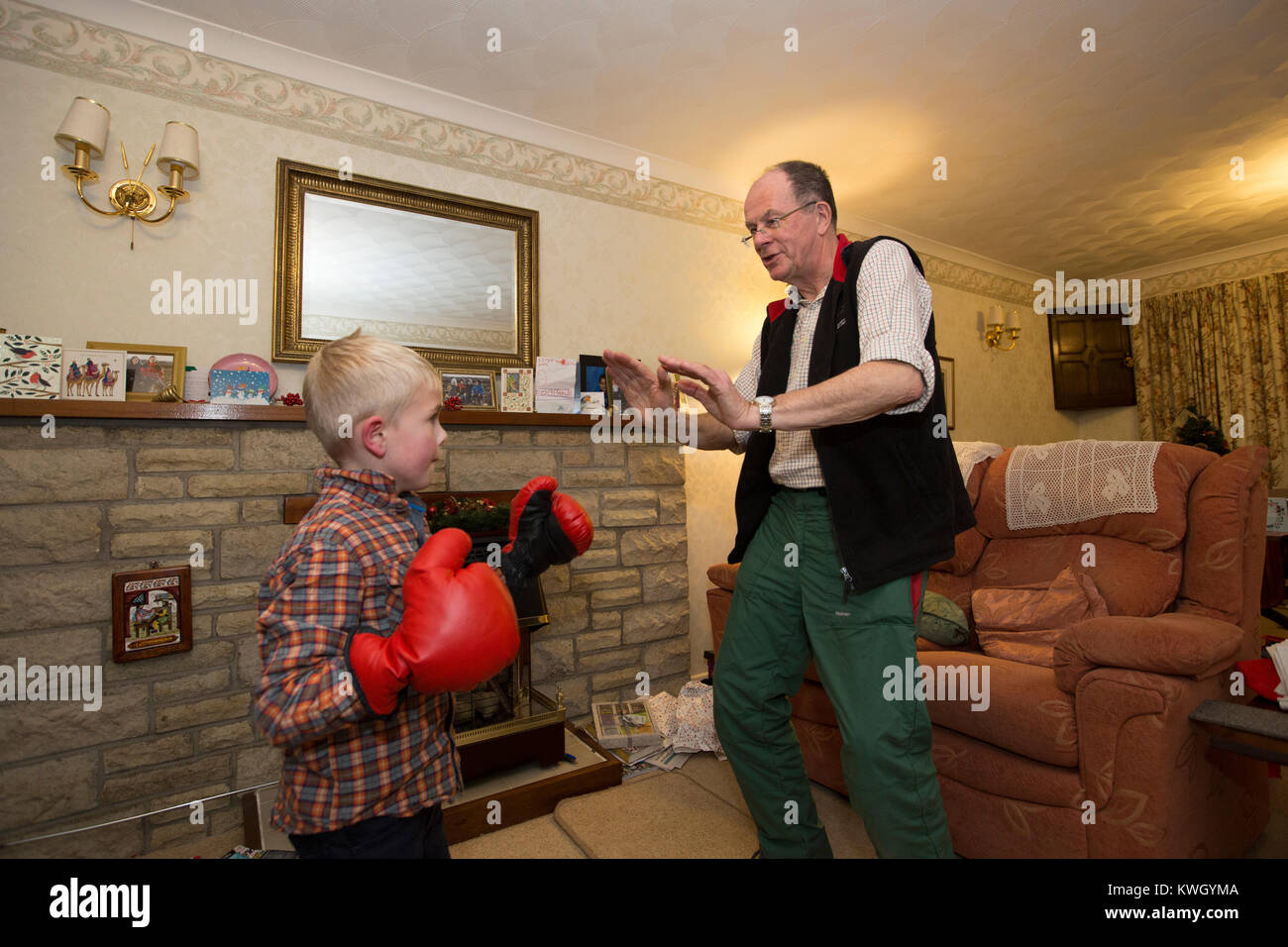 A Grandfather gives his young grandsons a boxing lesson inside the lounge of their residential home in the United Kingdom Stock Photo