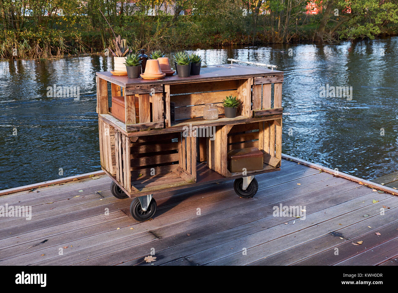 Home made storage furniture of wood boxes standing on a wooden jetty by a river Stock Photo