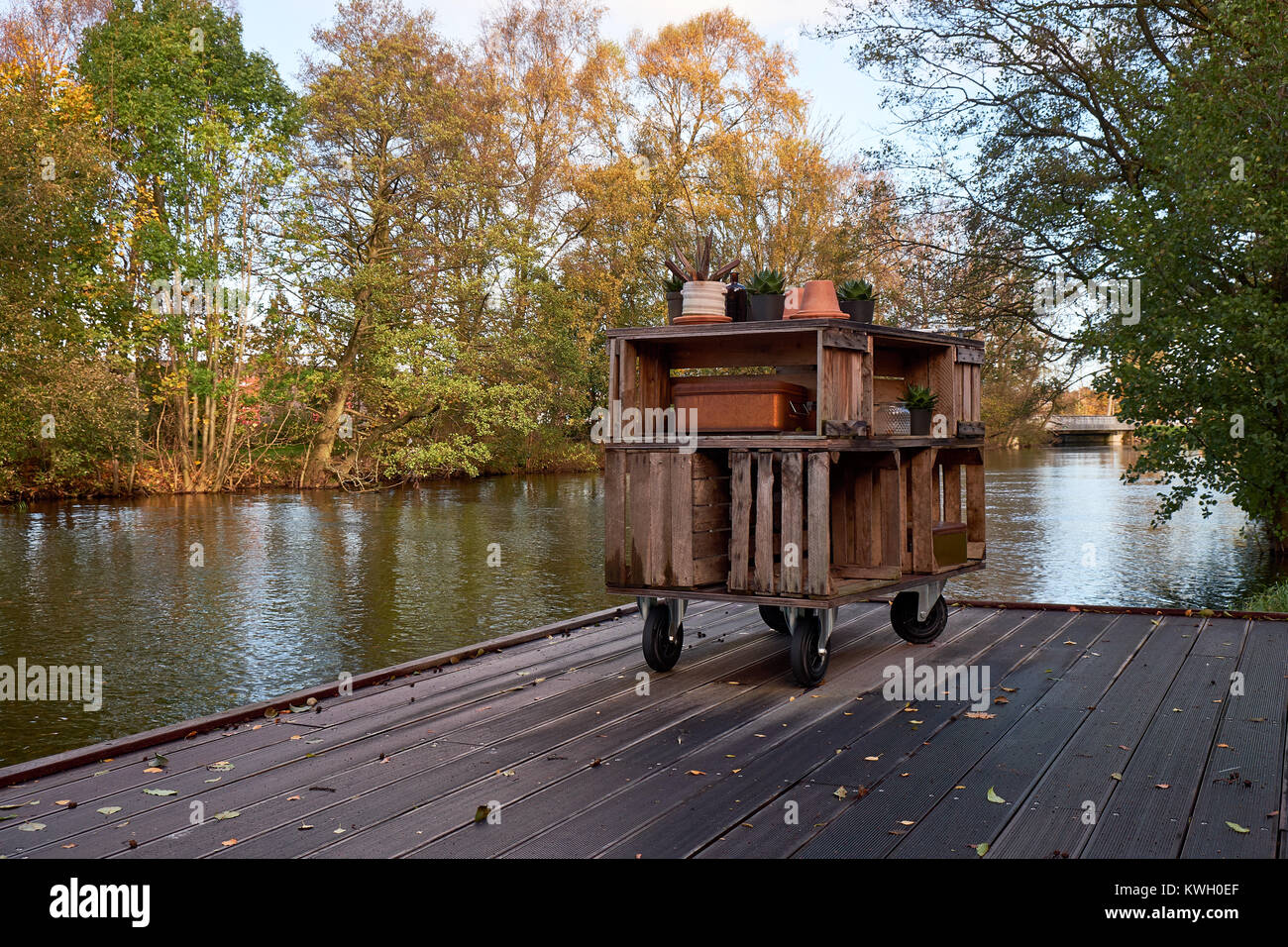Home made storage furniture of wood boxes standing on a wooden jetty by a river Stock Photo