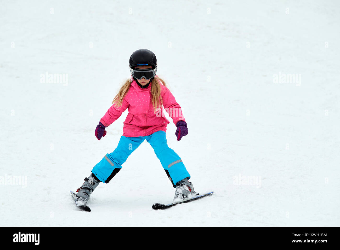 Child skiing in the mountains. Girl in colorful suit and safety helmet learning to ski. Winter sport for family with young children. Kids ski lesson i Stock Photo