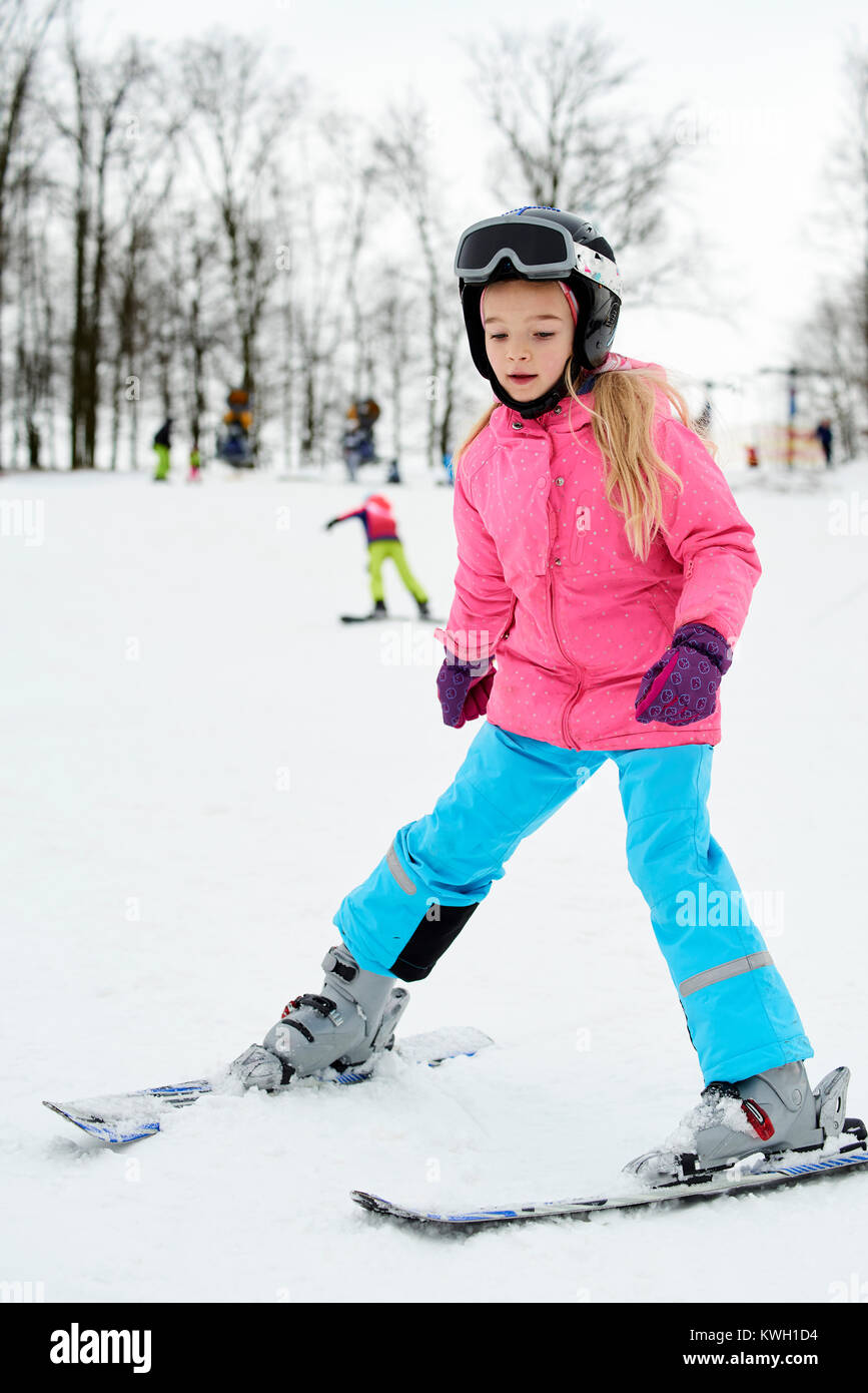 Child skiing in the mountains. Girl in colorful suit and safety helmet learning to ski. Winter sport for family with young children. Kids ski lesson i Stock Photo