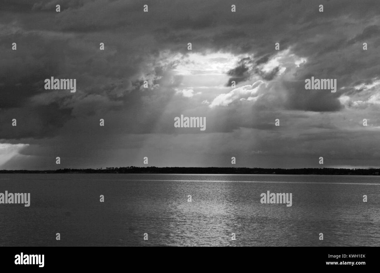 Black & white storm on Bay light shining through a break in clouds Stock Photo