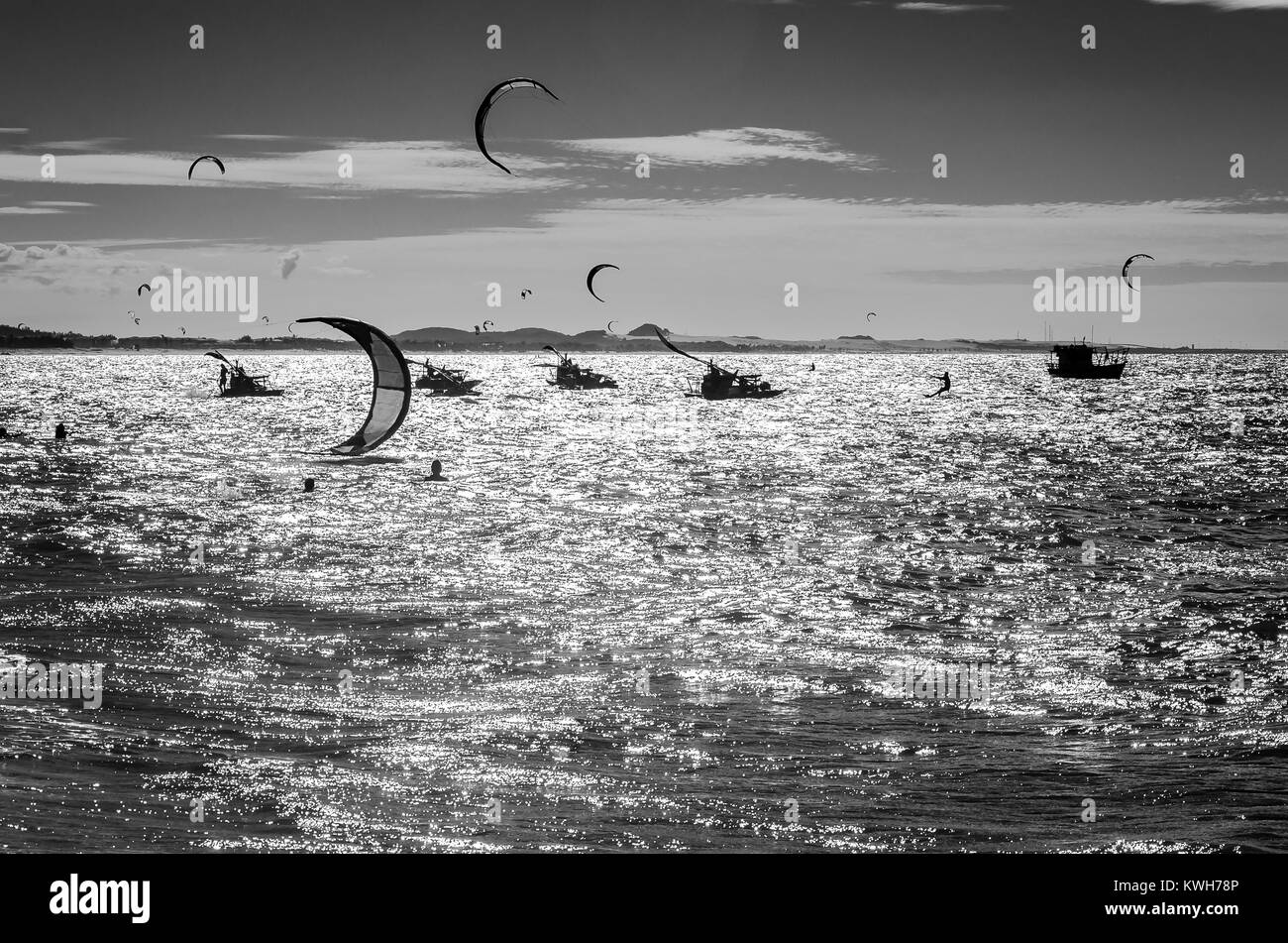 Black and white sunset with kite surfers enjoying the sea at evening ...