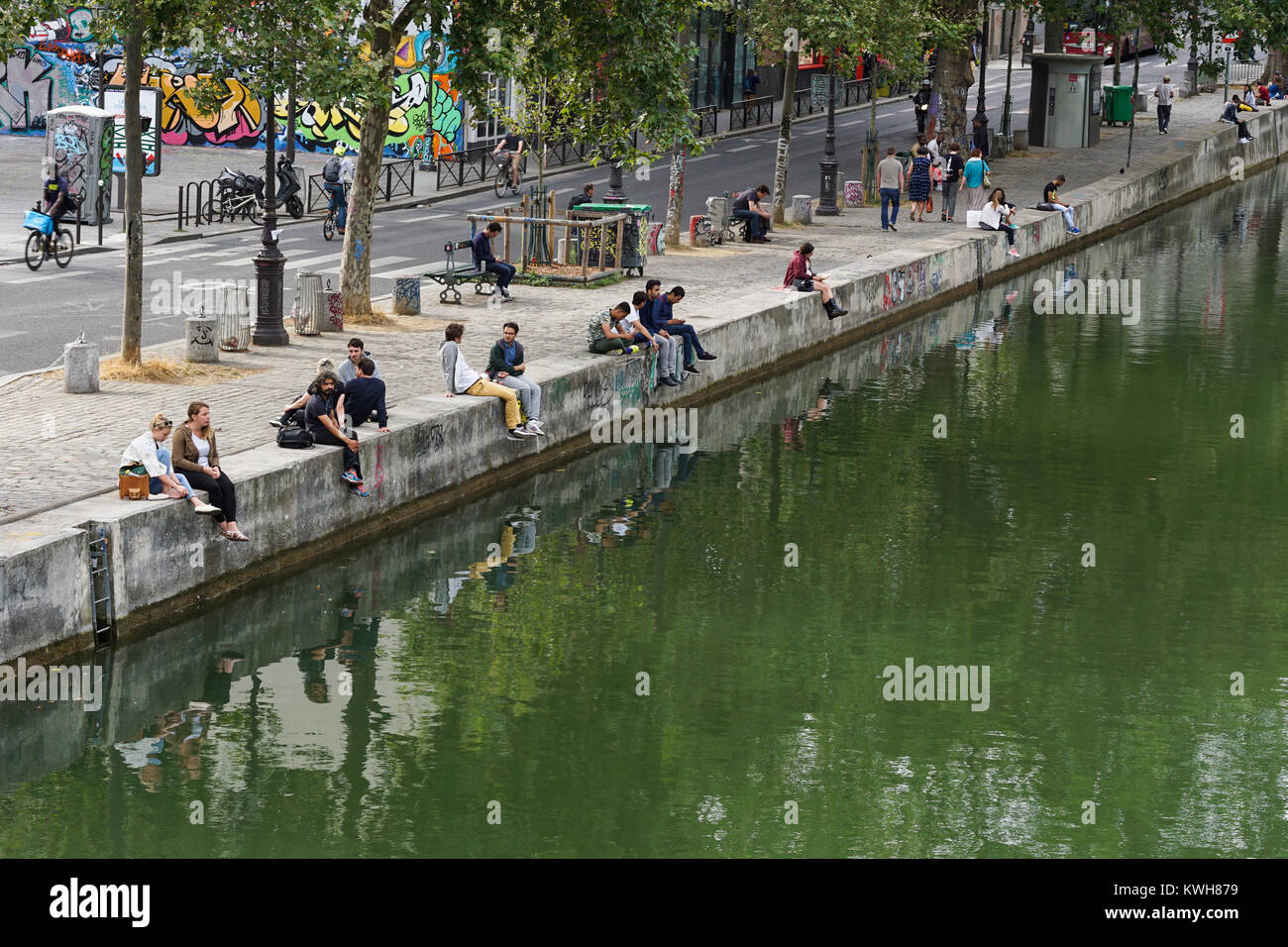 People sitting on the bank of the Canal Saint Martin in Paris. Stock Photo