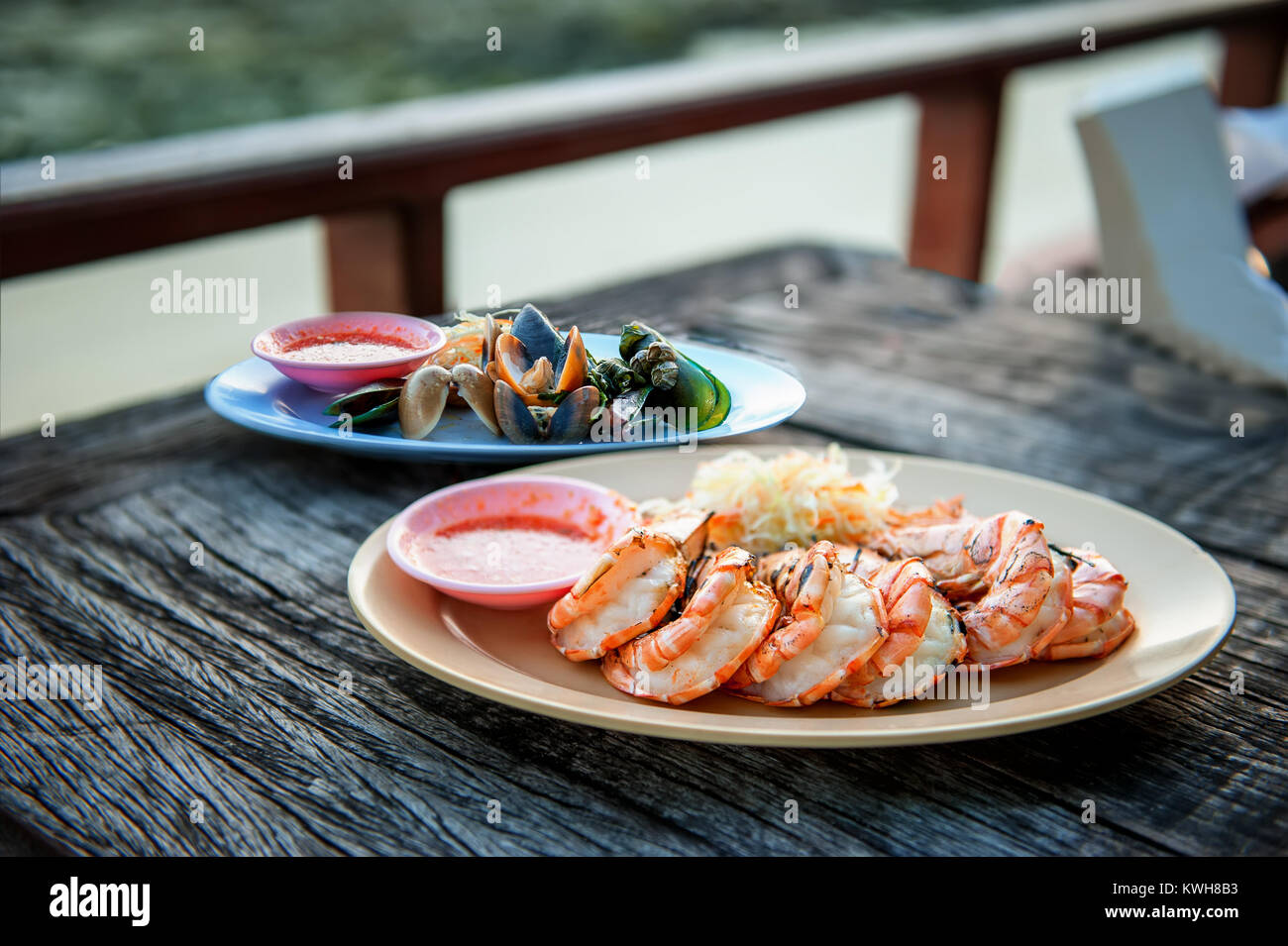 Oysters and lobster in white plate on table in cafe on the street a bright Sunny day. Stock Photo