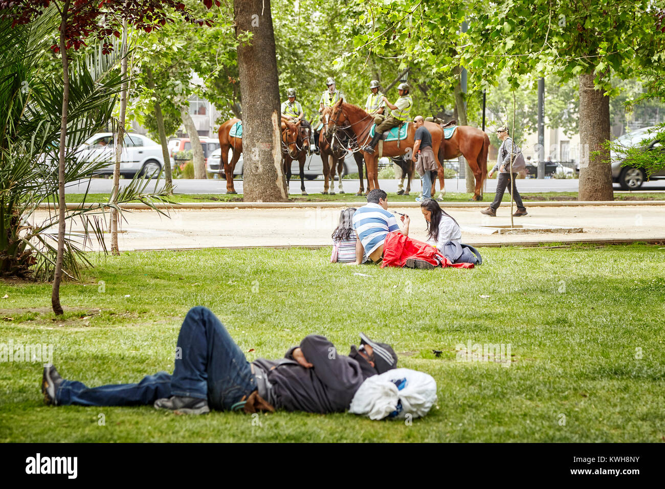 Santiago de Chile, Chile - October 24, 2013: People rest in a municipal park with mounted police in a distance (Carabineros de Chile). Stock Photo