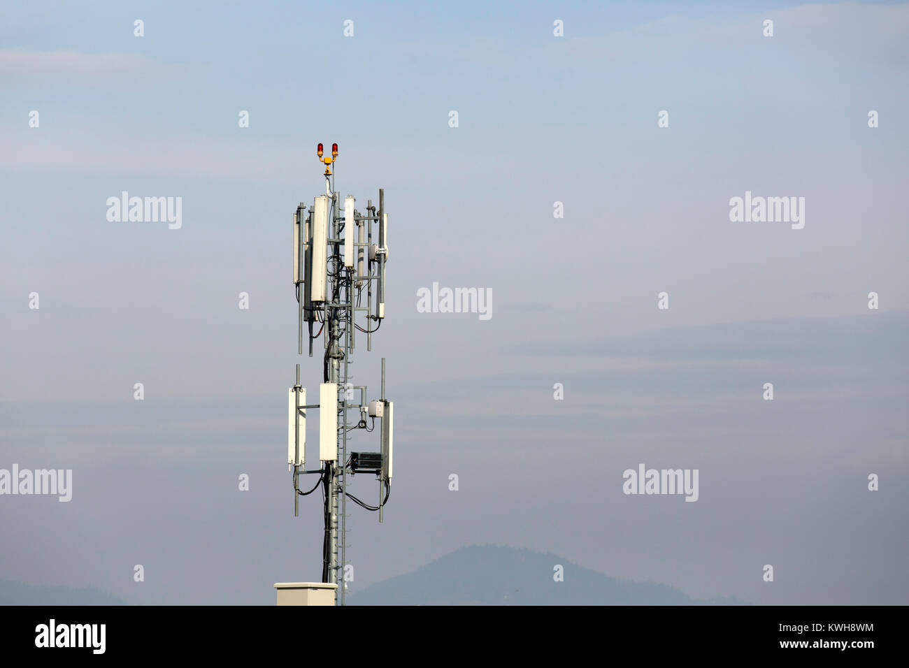 A base station for transmitting signals from mobile phones. The transmitters are mounted on a mast. Stock Photo