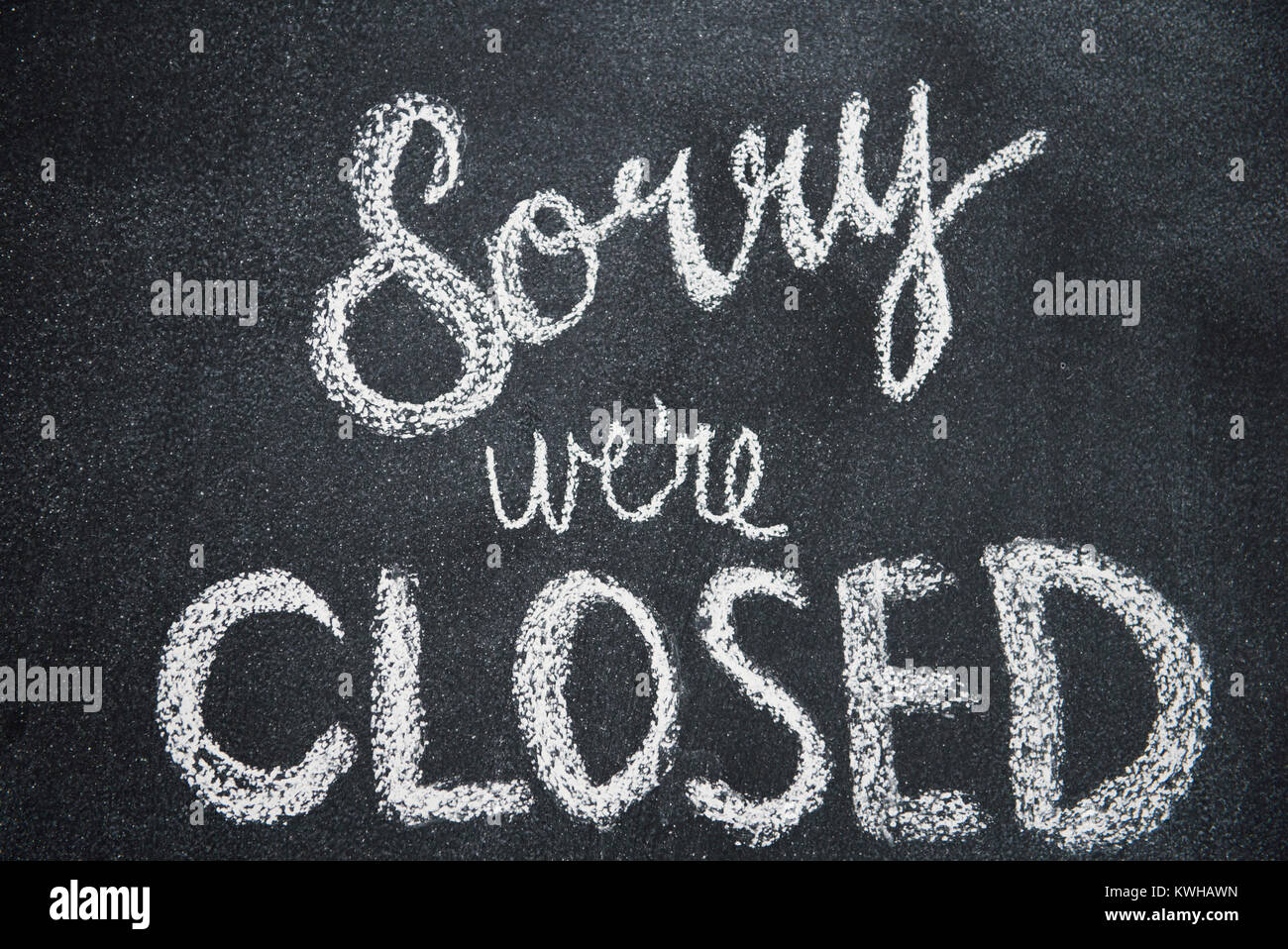 Sorry we're closed is shown written in white chalk on a blackboard Stock Photo