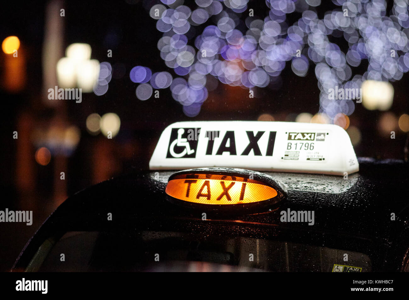 london taxi cab for hire sitting in the rain over festive period belfast northern ireland uk Stock Photo