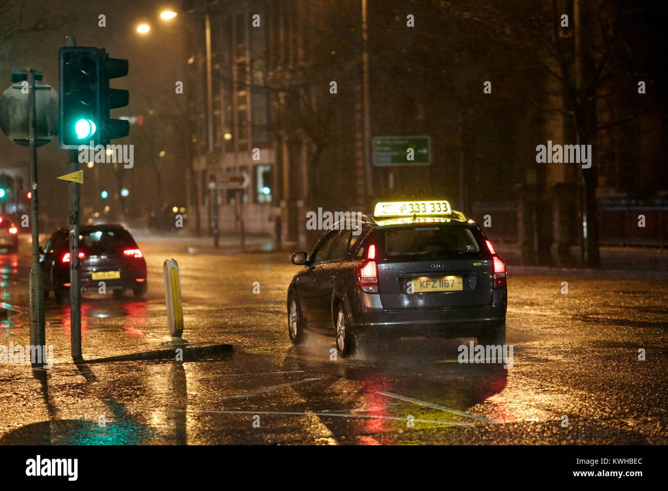 private cab driving through wet city streets at night belfast northern ireland uk Stock Photo