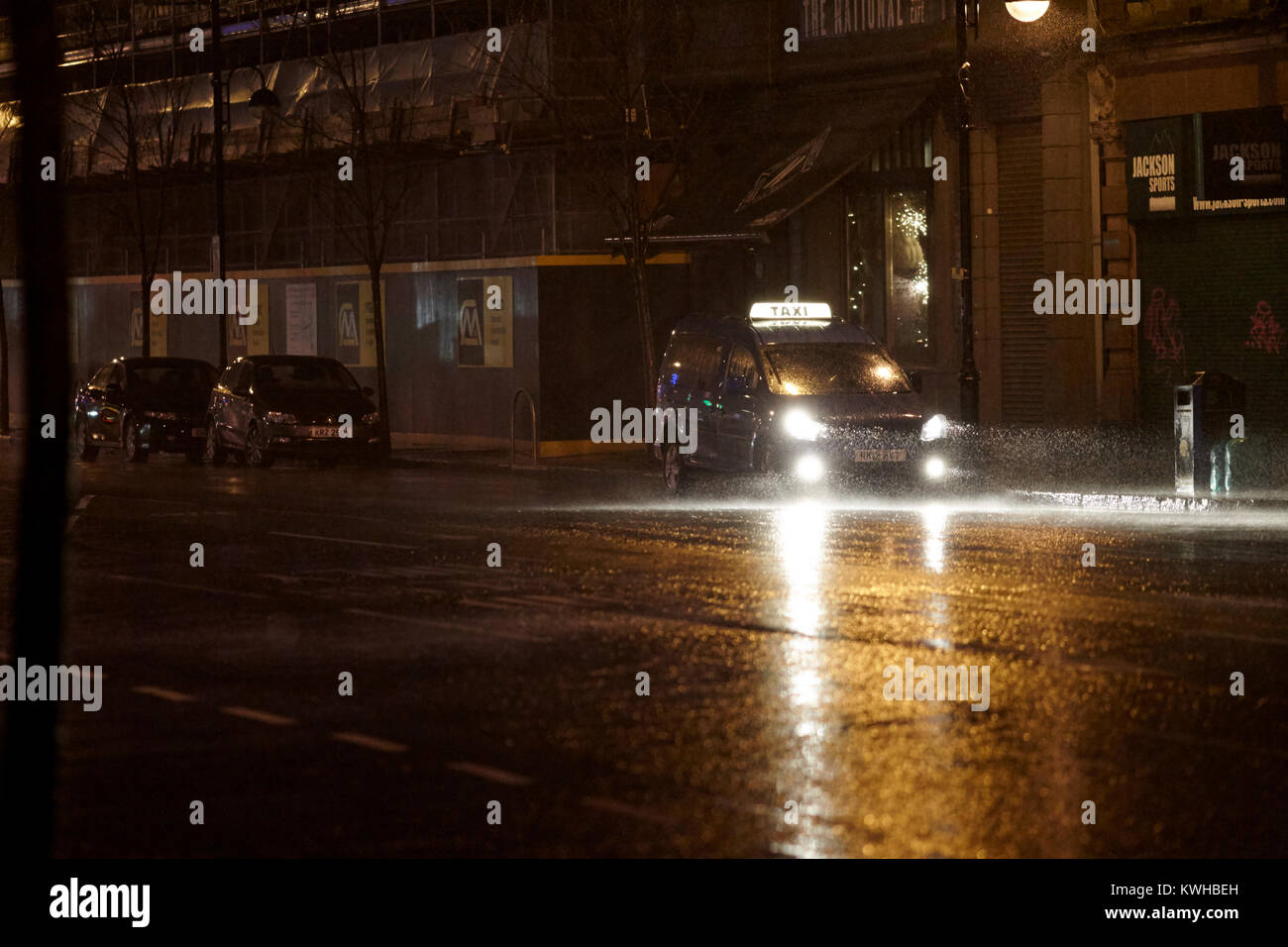 private cab waiting on far outside pub on wet windy night belfast northern ireland uk Stock Photo