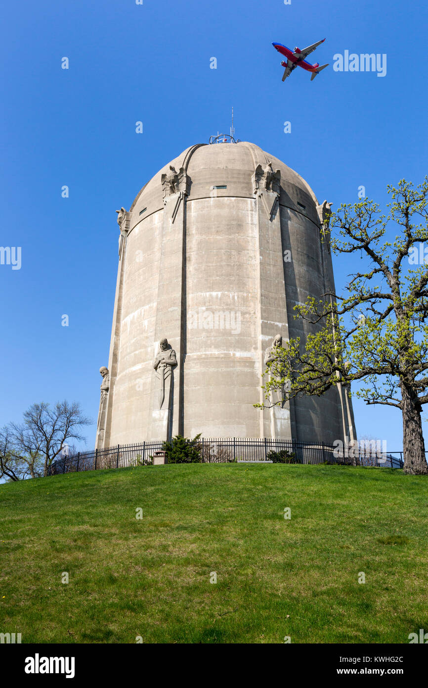 An airplane flying over the 1932 art deco Washburn Park Water tower in South Minneapolis, Minnesota.  The concrete water tower was designed by archite Stock Photo