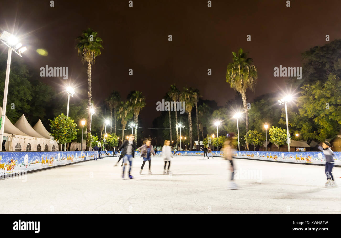 Ice skaters having fun on skating rink at traditional Christmas fair on