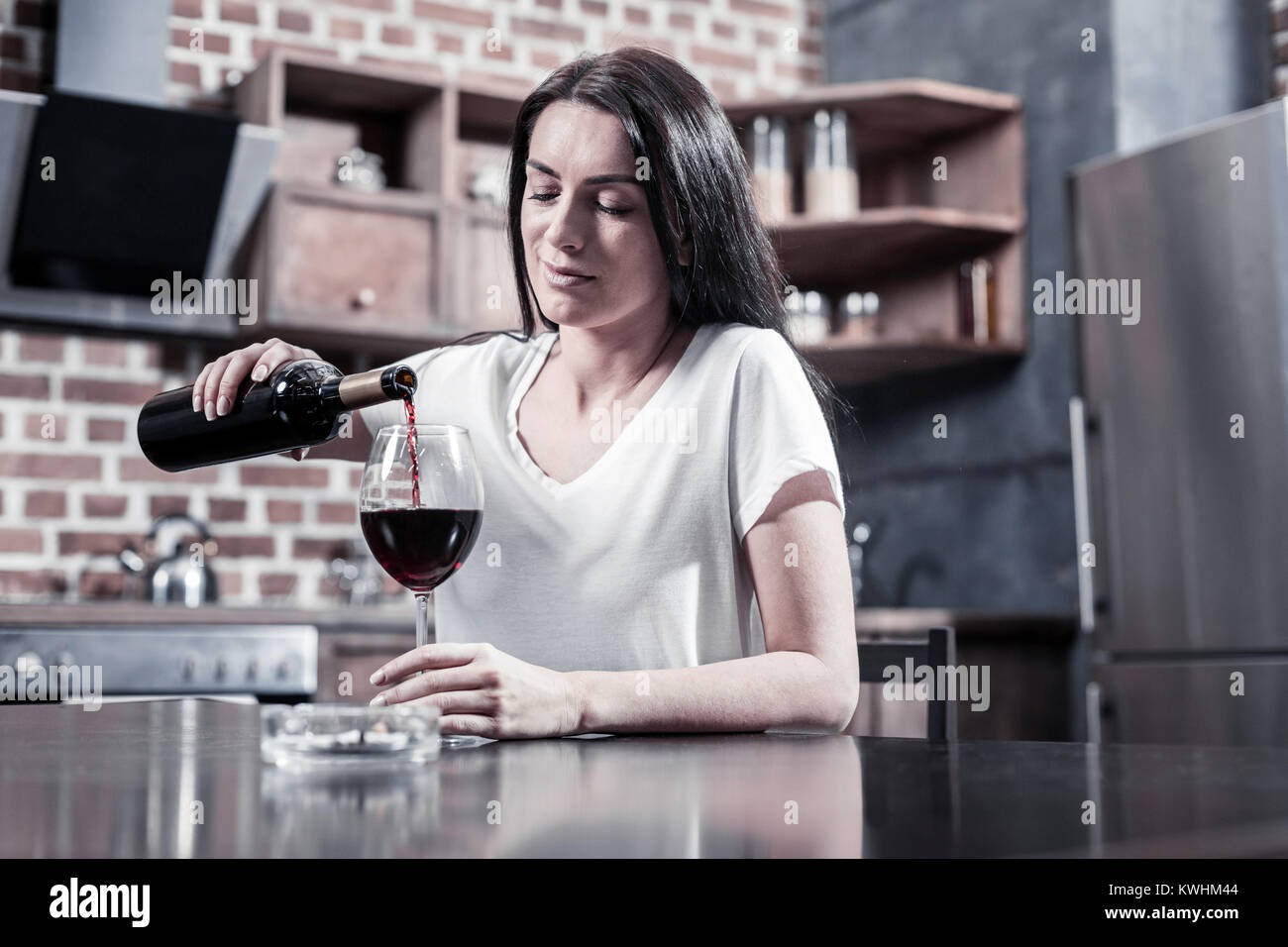 Sad brunette woman pouring wine Stock Photo
