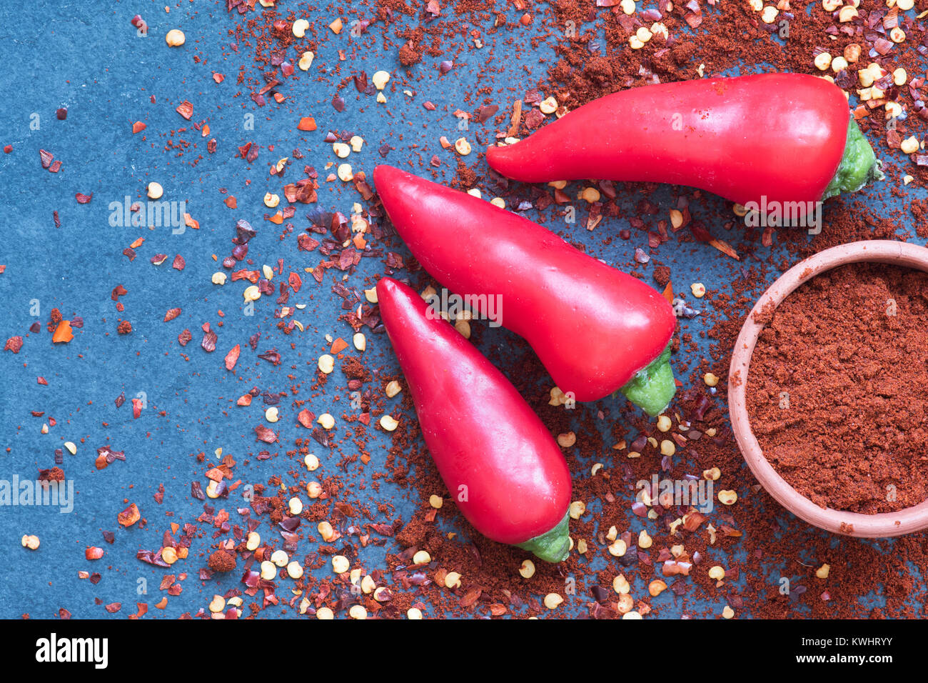 Capsicum. Red chili peppers, Chili powder and dried chili flakes on slate Stock Photo