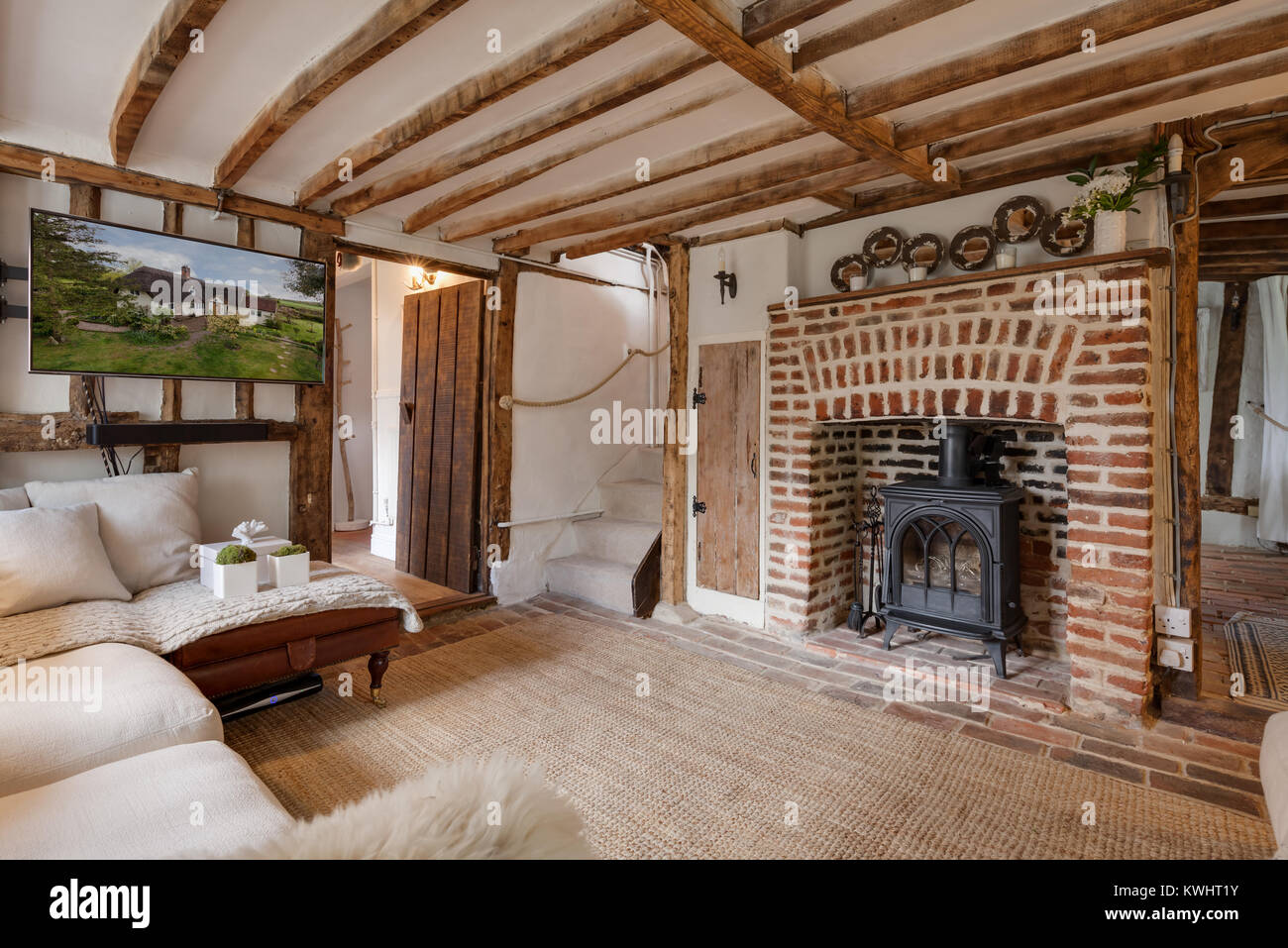 Small living room within 16th Century English timber framed cottage featuring an exposed brick fireplace with cast iron fire, numerous original featur Stock Photo