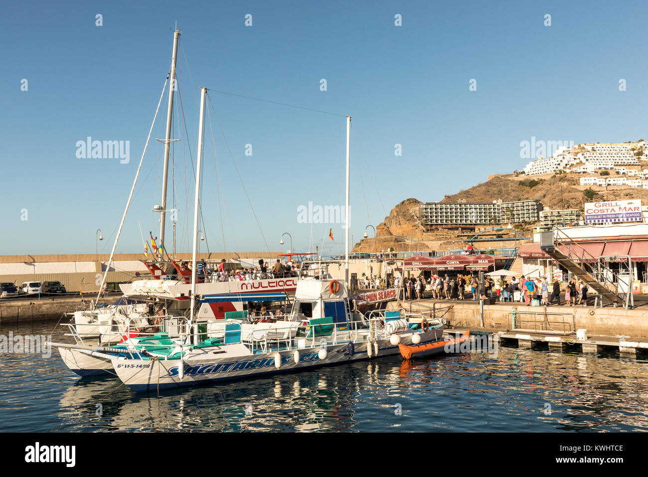 Puerto Rico, Gran Canaria - December 12 2017: Marina of Puerto Rico, tourists going on boat trips in the morning. Many companies offers boat trips for fishing and sightseeing. Stock Photo