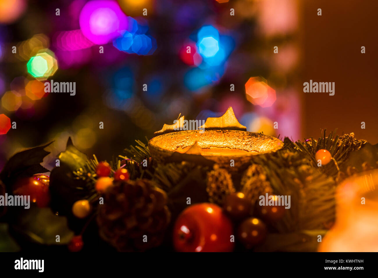 Christmas garland with candle and tree lights in background, festive warm ambience. Stock Photo