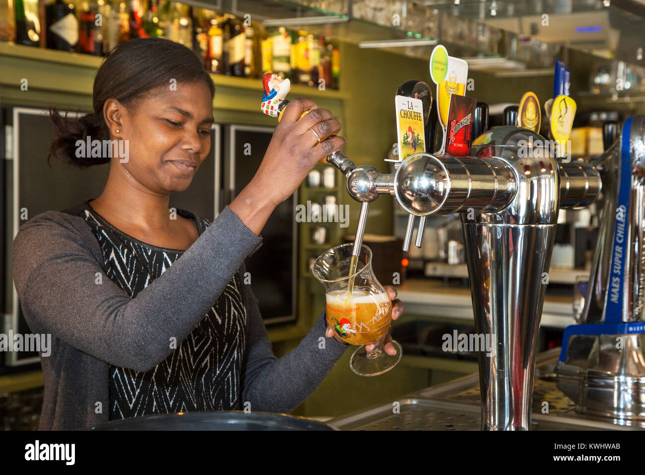 Black barmaid drawing Belgian draught beer in glass in Flemish tavern De Gulden Cop in the town Temse / Tamise, East Flanders, Belgium Stock Photo