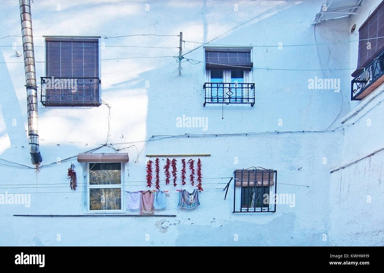 Red peppers and laundry hanging to dry on white roughcast wall in