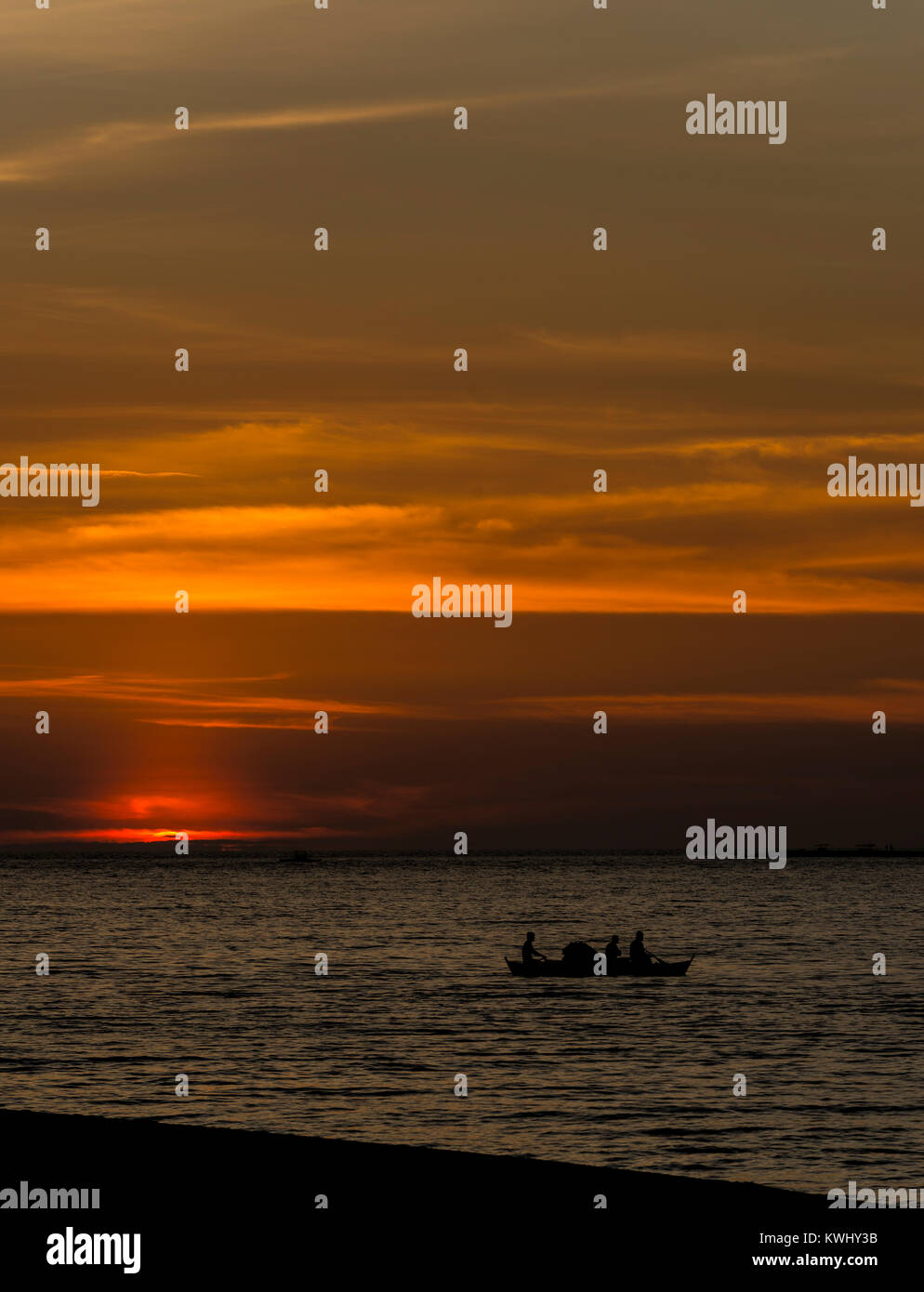Three fishermen in a small boat out on the ocean at sunset Stock Photo ...