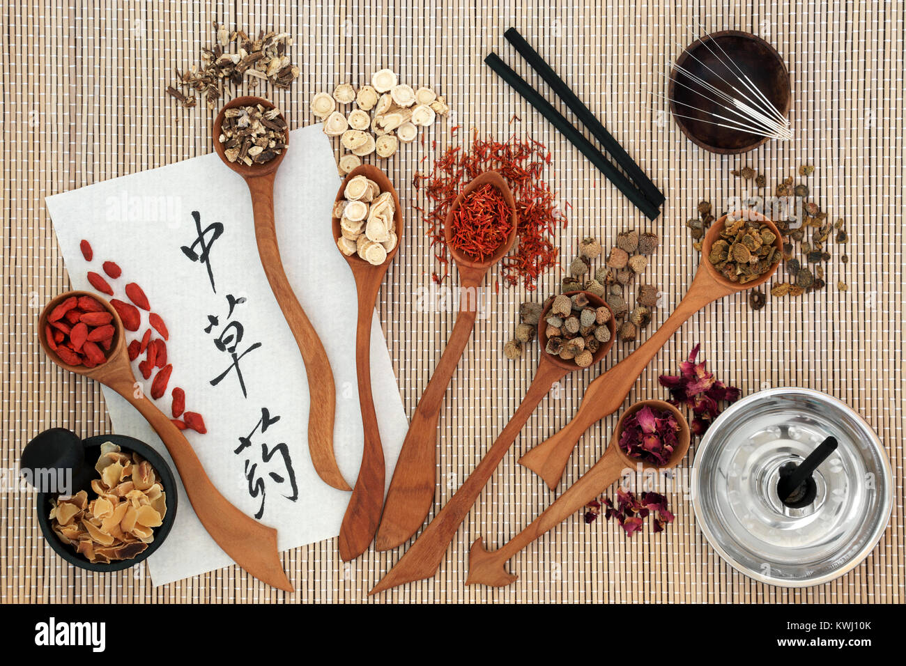 Chinese acupuncture needles and moxa sticks used in moxibustion therapy with herbs and calligraphy script on rice paper. Stock Photo