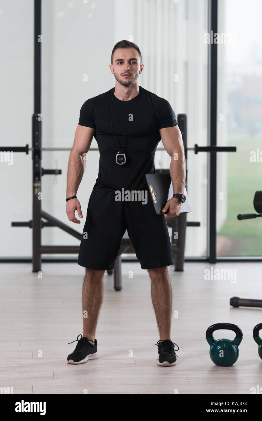 Personal Trainer In Sports Outfit Takes Notes On Clipboard In A Fitness  Center Gym Standing Strong Stock Photo - Alamy