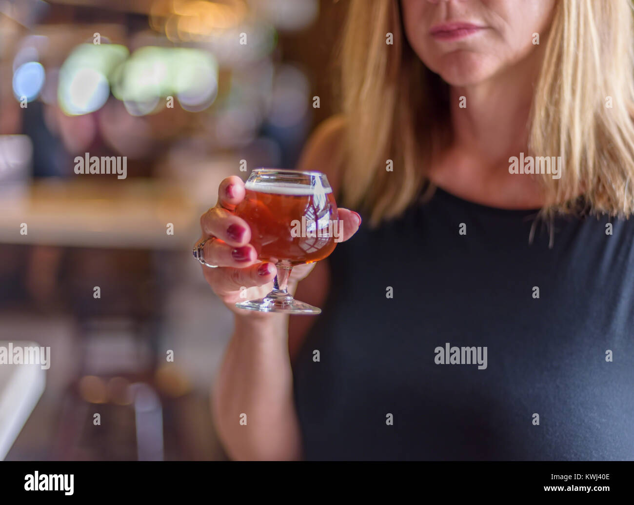 attractive woman holding a glass of microbrew at a local taproom Stock Photo