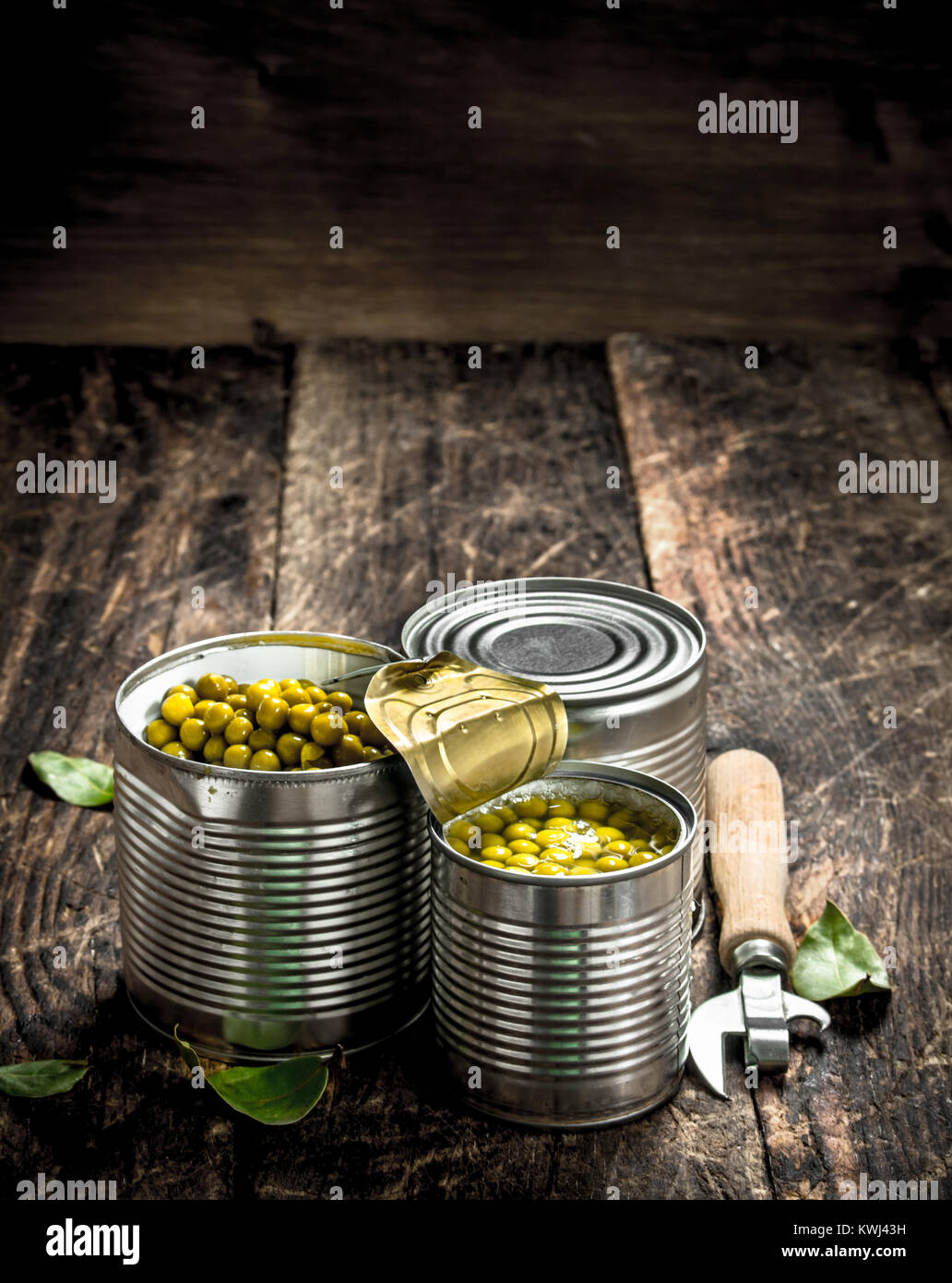 Canned green peas in a tin can with opener. On a wooden background