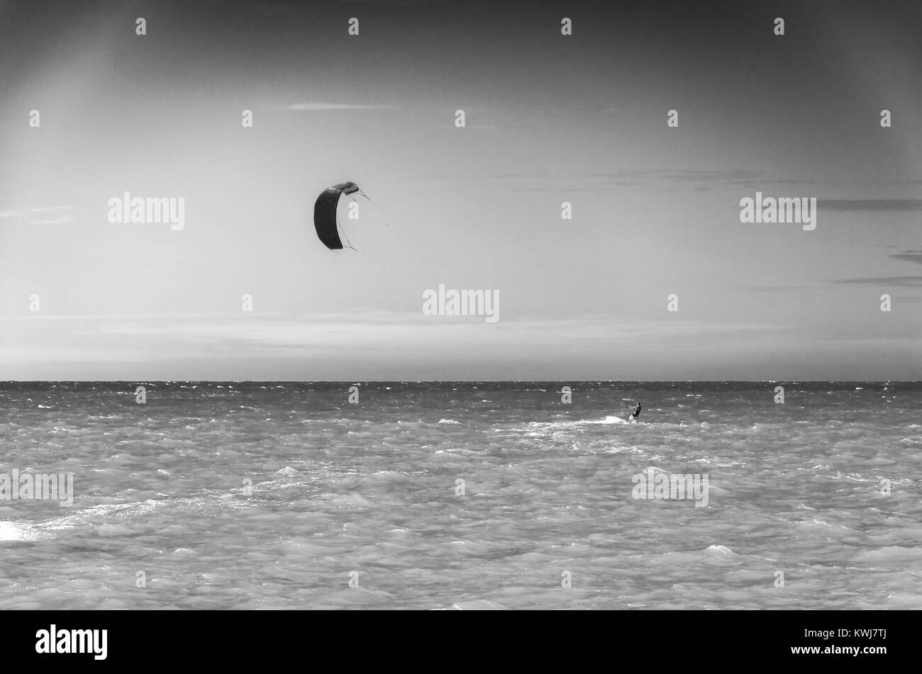 Black and white sunset with kite surfers enjoying the sea at evening ...