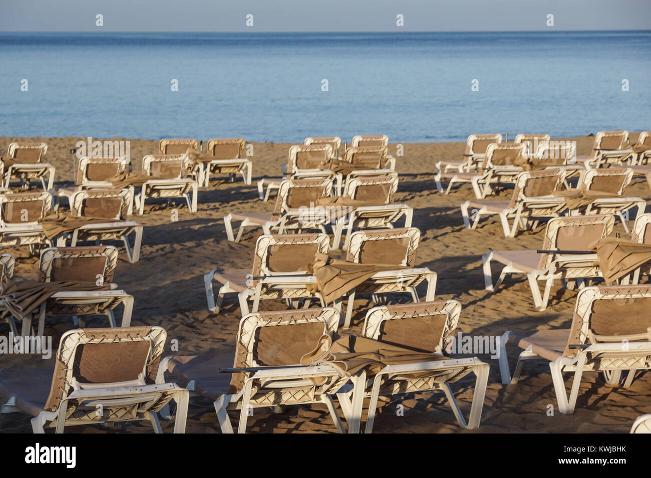 Sun loungers and closed umbrellas at a seaside resort , the calm and relaxed atmosphere of the summer holiday Stock Photo
