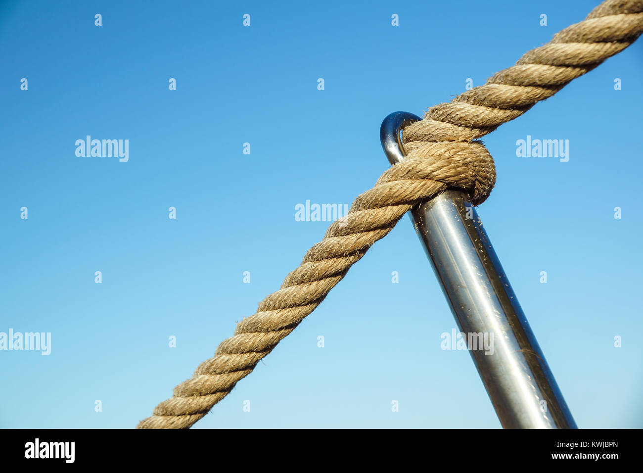 Detail of rope railing of beach walkway, old metal pole, seaside ...
