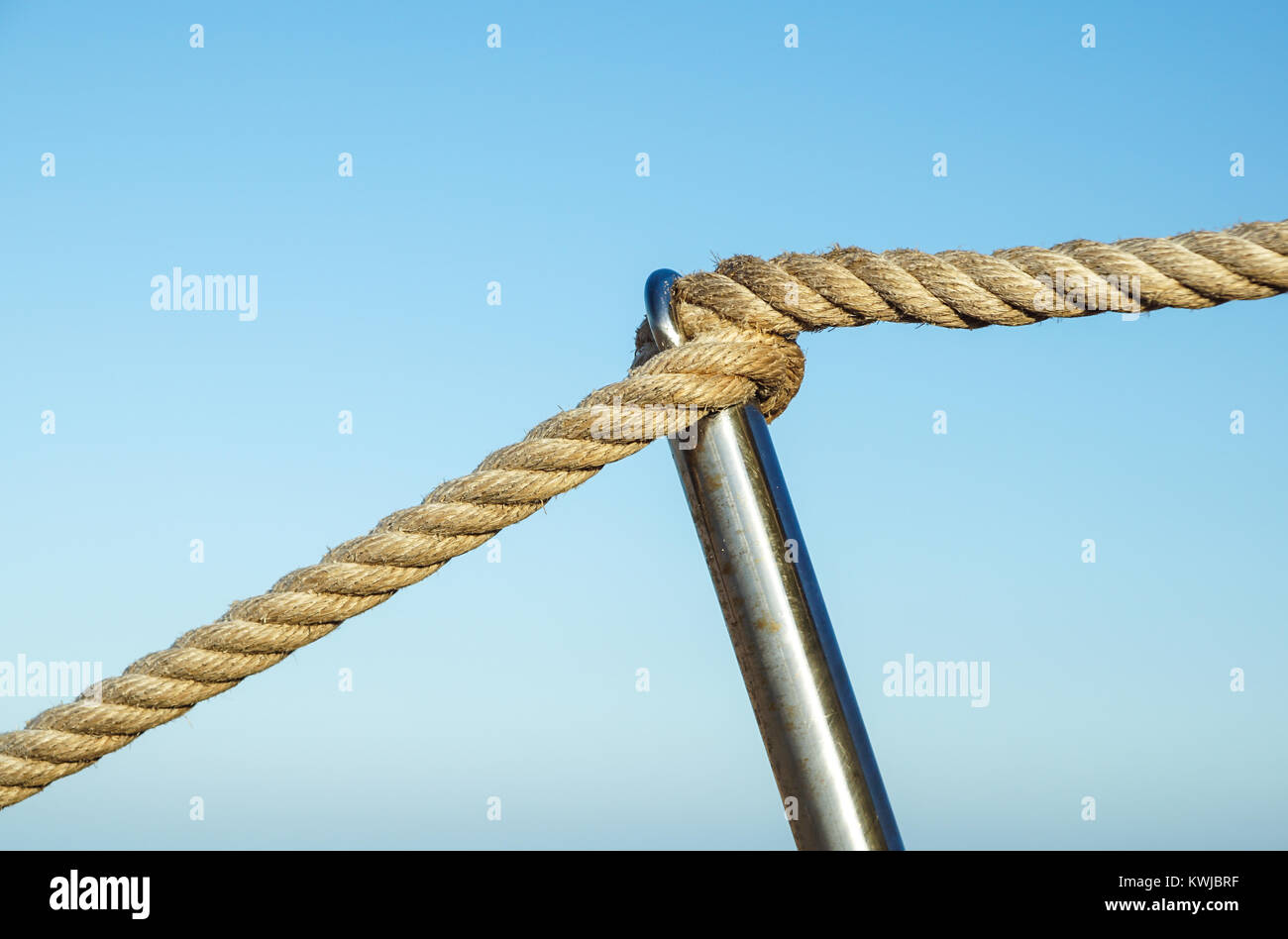 Detail of rope railing of beach walkway, old metal pole, seaside ...