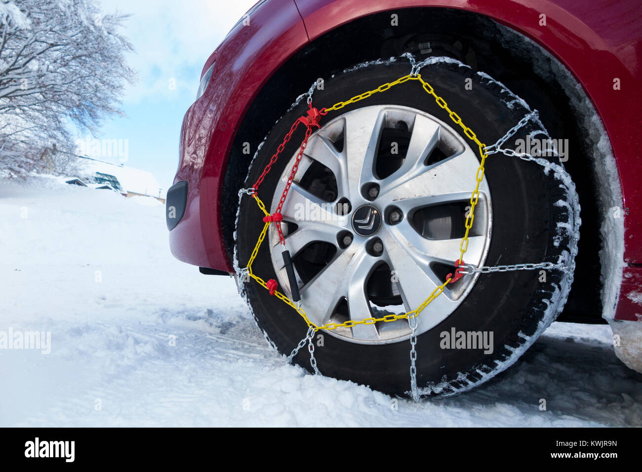 Snow chain / chains on front wheel / wheels / tyres / tires of a car in freezing winter weather