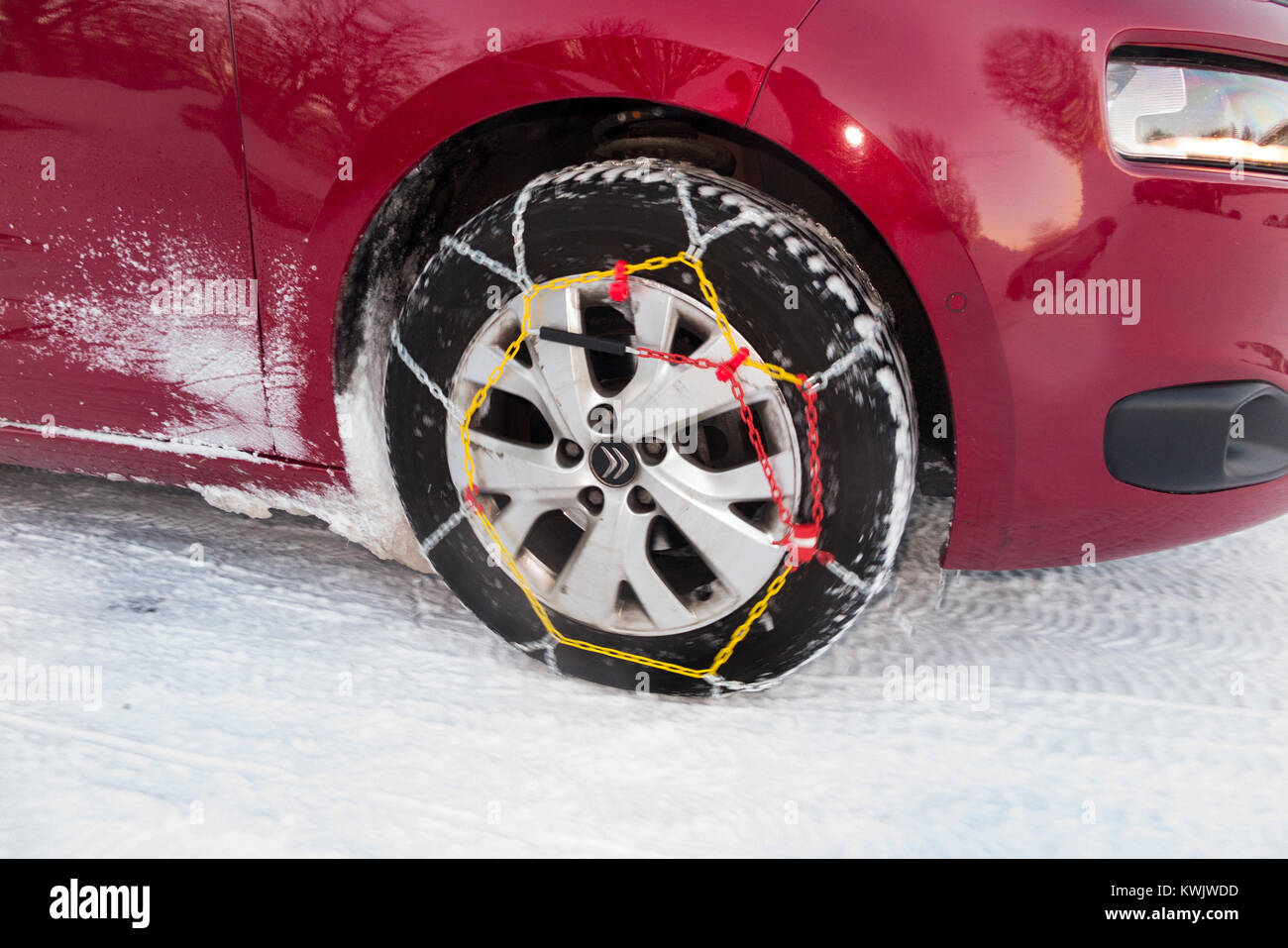 Snow chain / chains on front wheel / wheels / tyres / tires of a car in freezing winter weather