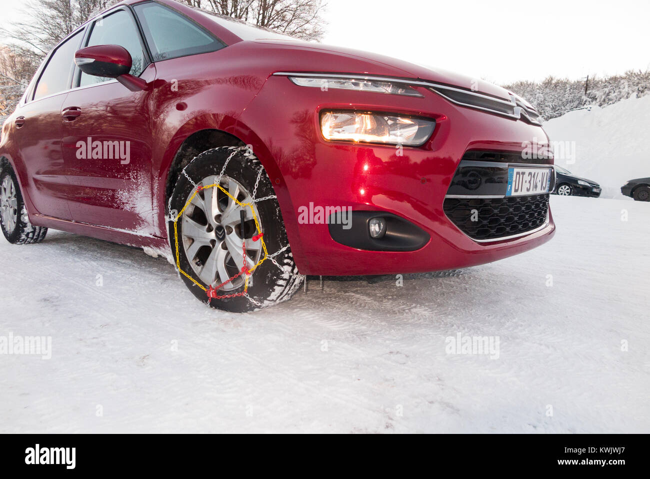 Snow chain / chains on front wheel / wheels / tyres / tires of a car in freezing winter weather