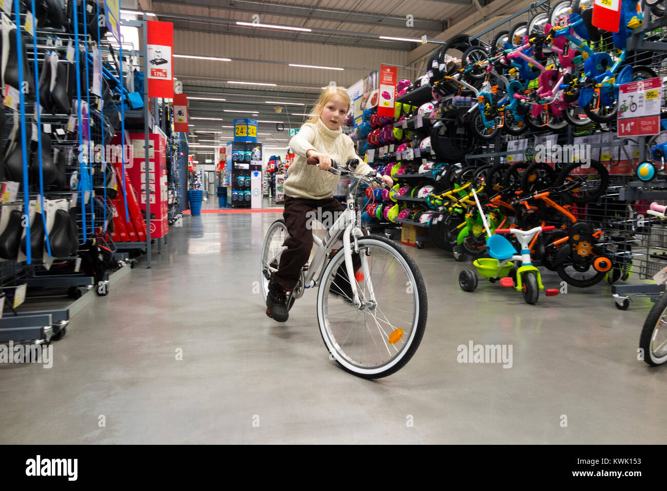 Young girl rider aged 7 years old rides / riders take bicycles / new bicycle / cycles for a test cycle at a bike shop before buying, on holiday. (93) Stock Photo