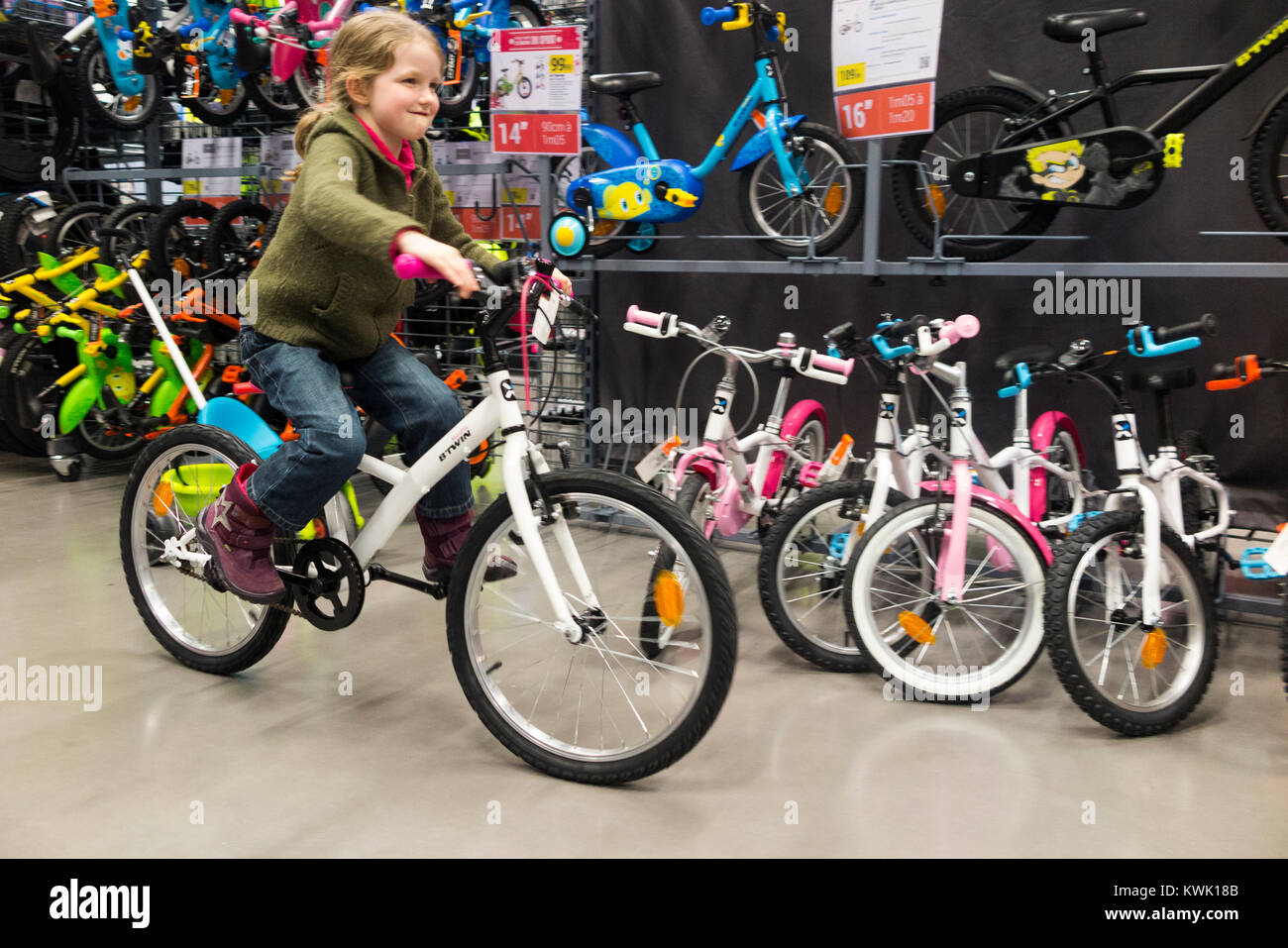 Young girl rider aged 5 years old rides / riders take bicycles / new bicycle / cycles for a test cycle at a bike shop before buying, on holiday. (93) Stock Photo