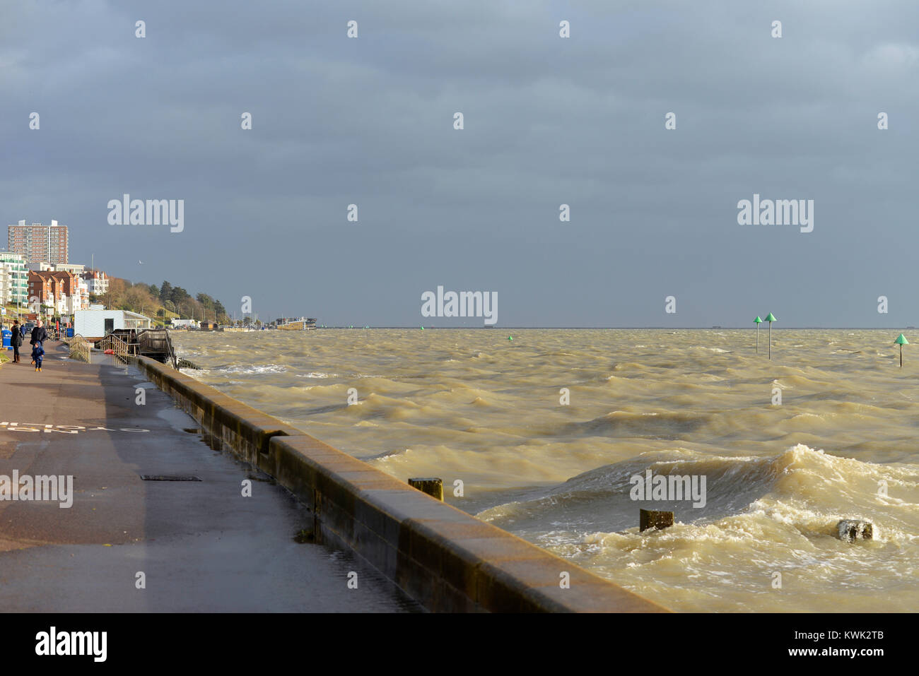 Family walking along the seafront during Storm Eleanor at Southend on Sea, Essex. Stormy waters of Thames Estuary with Southend Pier beyond Stock Photo