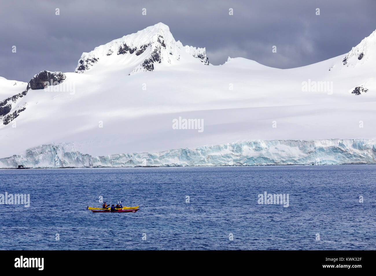 Kayakers explore snow covered Antarctica; Half Moon Island Stock Photo