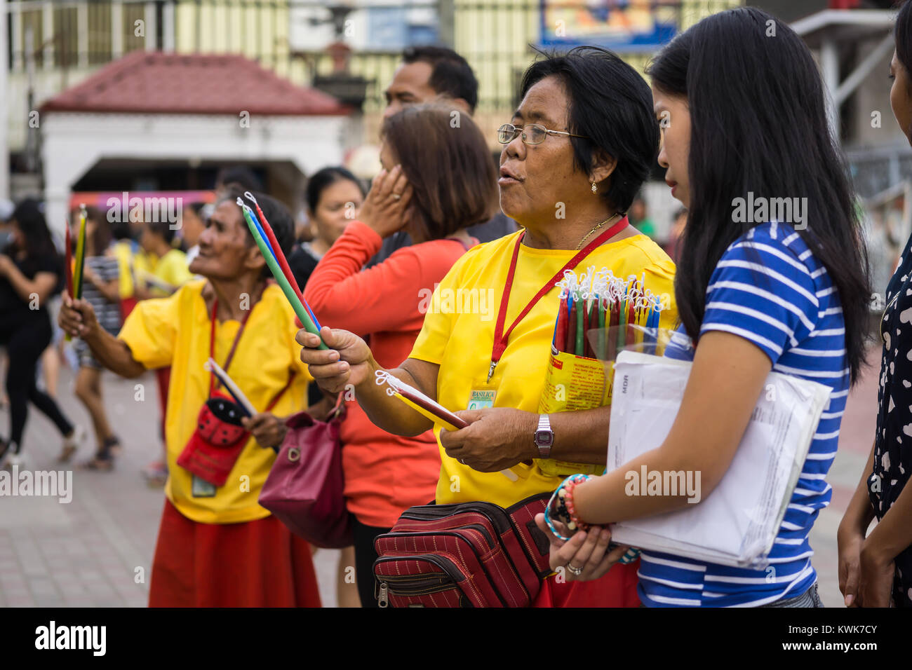 Roman Catholic Filipino women selling candles within the Basilica Del Santo Nino,Cebu carry out a prayer ritual for individuals purchasing candles Stock Photo