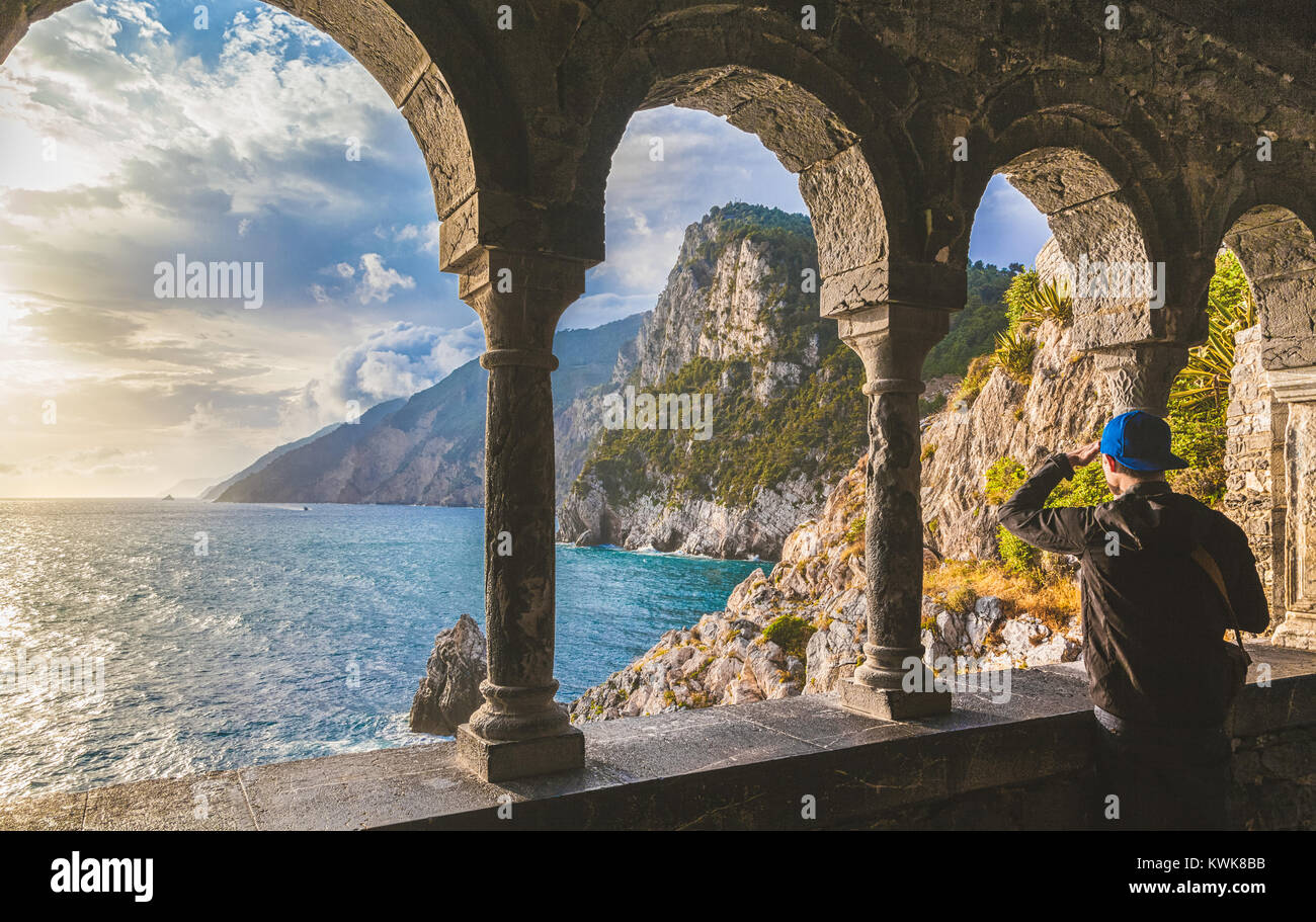Young man enjoying scenic ocean view during sunset at famous gothic Church of St. Peter (Chiesa di San Pietro) in Porto Venere, Liguria, Italy Stock Photo