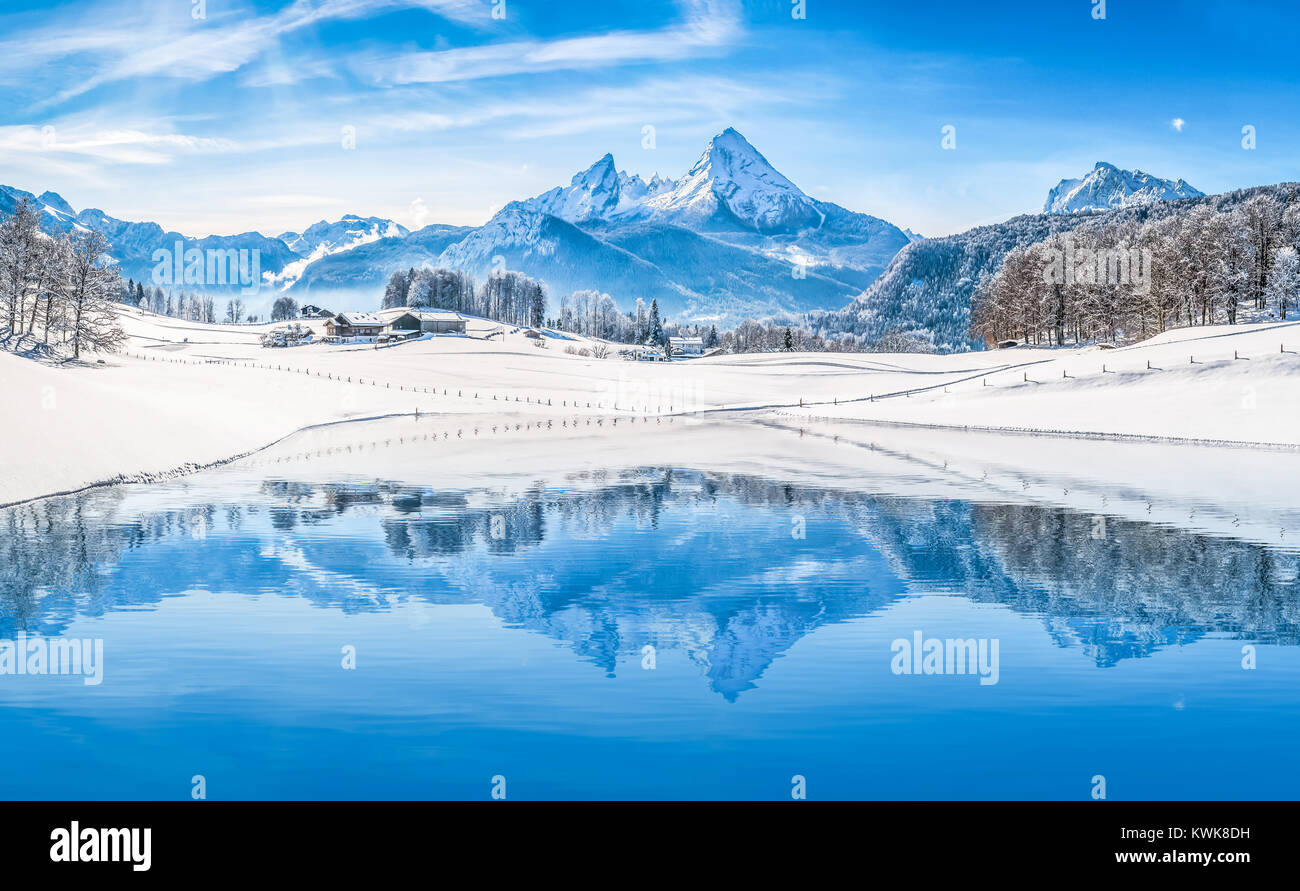 Panoramic view of beautiful white winter wonderland scenery in the Alps with snowy mountain summits reflecting in crystal clear mountain lake Stock Photo