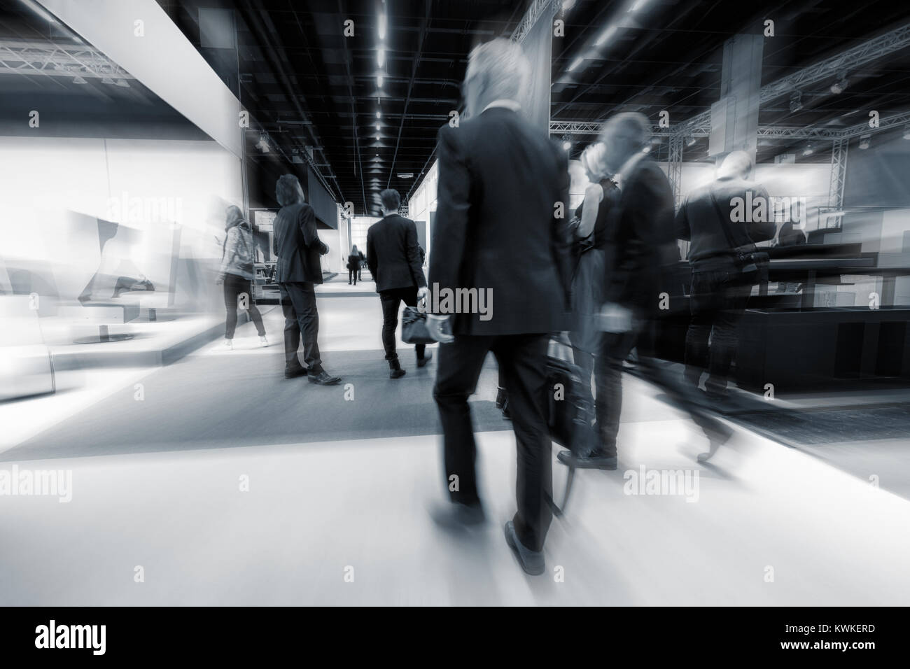 blurred business people walking between at trade show booths. Stock Photo