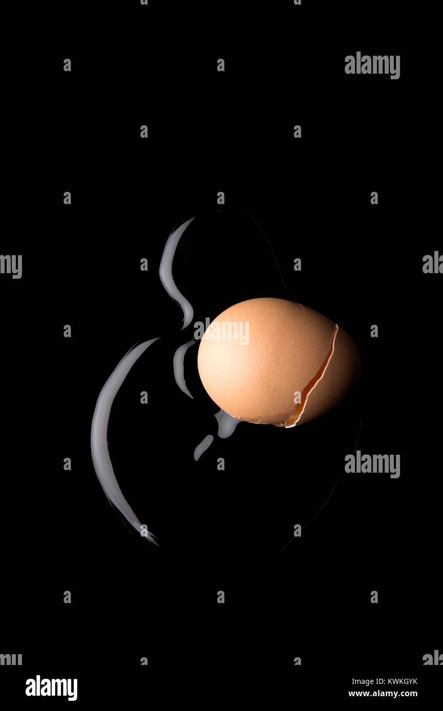 Concept image of a cracked egg on a black background Stock Photo - Alamy