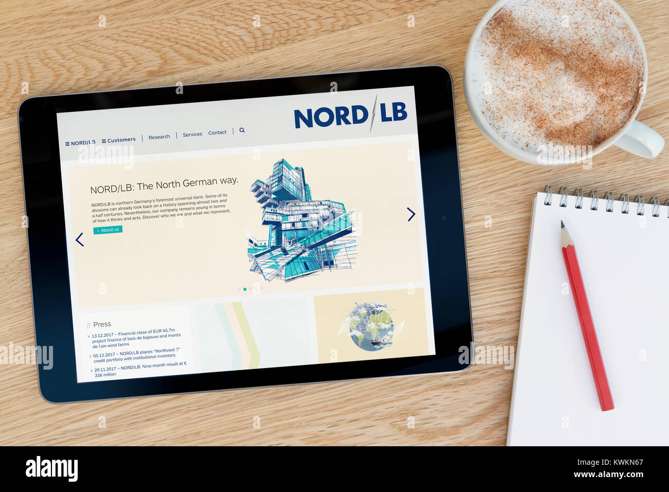 The Nord/LB website on an iPad tablet device, resting on a wooden table beside a notepad, pencil and cup of coffee (Editorial only) Stock Photo